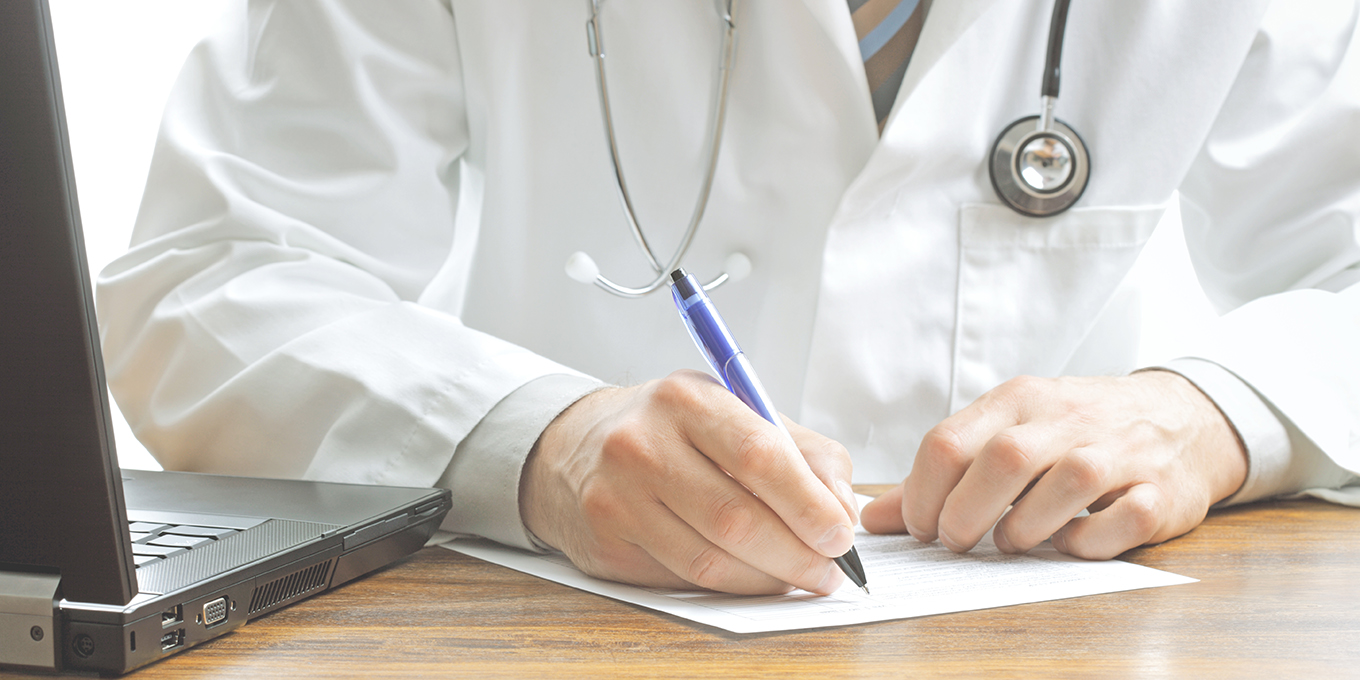 Doctor writing patient notes on a medical examination or prescription